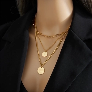 Layered gold titanium steel necklace with engraved coin pendants on a model in black suit
