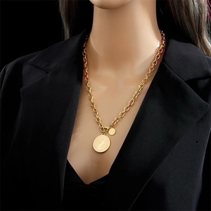 Vintage gold portrait coin pendant necklace on thick chain worn over black suit