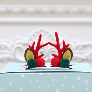 Détail de pinces à cheveux de Noël avec bois de renne et pompons sur boîte cadeau