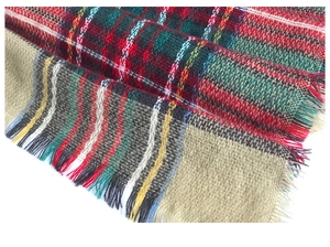Close-up of red and green plaid faux cashmere fabric texture with fringe details
