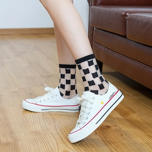 Transparent black socks with square patterns worn with white canvas shoes on wood floor