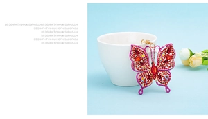 Close-up of gold butterfly keychain with red and pink rhinestones on a ceramic cup