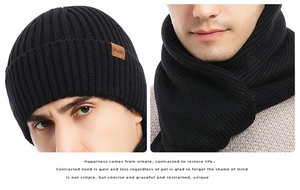 Close-up of black ribbed knit beanie and scarf set featuring a brown leather brand patch