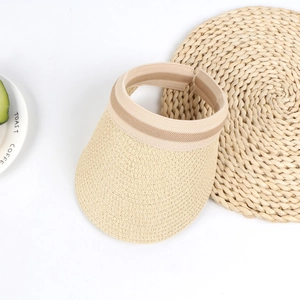 Detail view of woven straw sun hat with striped elastic band on a white surface
