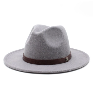 Detail of grey wool fedora hat featuring a brown leather band and vintage metal badge