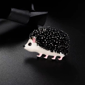 Macro view of cute hedgehog brooch with drip glaze finish on black satin background