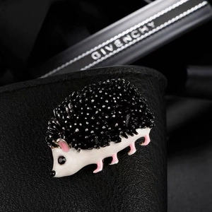 Close-up of cute hedgehog brooch with black crystals and white enamel finish