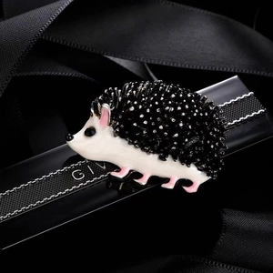 Detail of cute hedgehog brooch featuring glossy enamel and sparkling black rhinestones