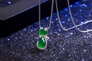 Macro shot of silver cat pendant with green gemstone and zircon on a starry background