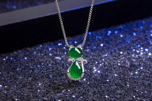 Close-up of cat pendant necklace with green agate gems on a sparkling blue background