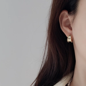 Detail of wide polished gold S925 silver stud earrings on a model with minimalist style