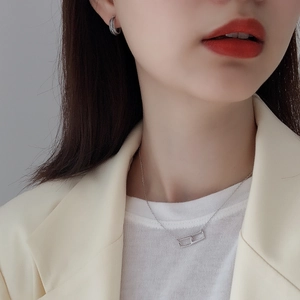 Detail of silver geometric pendant necklace and woven texture earrings on a model