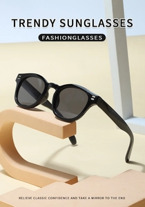 Detail of black frame sunglasses with metal studs on minimalist orange display stand
