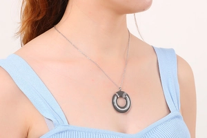 Close-up of a hollow circular pendant with sparkling crystals on a delicate silver chain