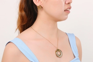 Model wearing a gold-plated circular jewelry set with rhinestones on a white background