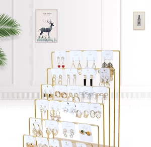 Detailed side view of five-tier golden metal jewelry display stand with earrings