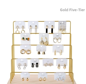 Detailed view of a 5-tier gold metal jewelry organizer with a solid wood base