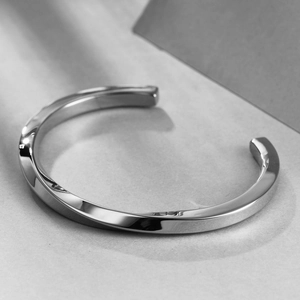 Detail shot of a minimalist silver polished twisted open bangle made of sleek titanium steel