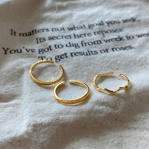 Detailed view of three 925 sterling silver gold rings on a linen pouch showing S925 hallmark