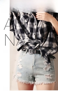 Detail view of a black faux leather belt with alloy pin buckle on denim shorts
