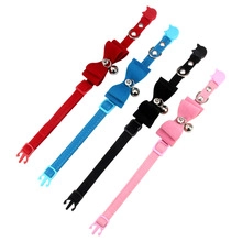 Detalle de cuatro collares de cuero para perros con lazos y cascabeles en rojo azul negro y rosa