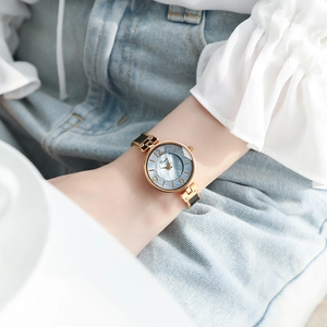 Detailed close-up of a vintage oval gold watch with a blue-grey mother-of-pearl dial on a wrist