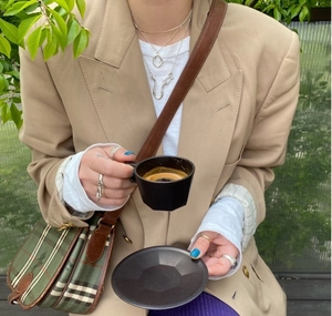 Chic matte black geometric coffee cup and saucer set featured in a lifestyle fashion setting
