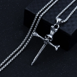 Macro shot of silver skull and cross pendant necklace on a black textured jewelry box