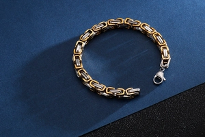 Detail of two-tone Byzantine chain bracelet with secure lobster clasp on blue background