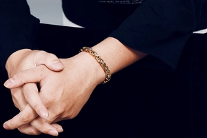 Close-up of men's two-tone gold and silver stainless steel mechanical link bracelet on wrist