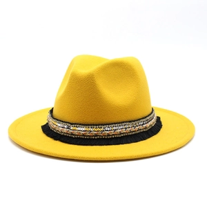 Detail of yellow wool fedora hat featuring ethnic ribbon with sequins and black tassels