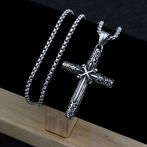 Detailed view of silver cross pendant with intricate carving on a black display stand