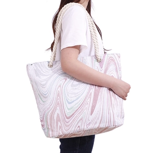 Detail of canvas tote bag with marble print and thick hemp rope handle shown on model