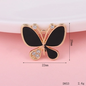 Detailed view of a gold butterfly charm with black enamel, rhinestones and size markings
