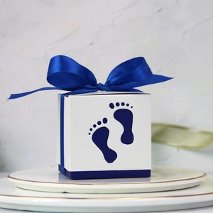 European style hollow baby footprint candy box with a blue ribbon on a ceramic plate