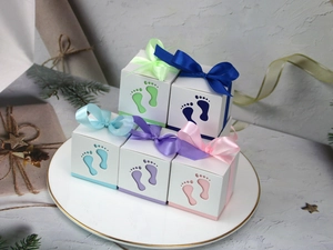 Detail view of hollow baby footprint candy boxes in five pastel colors with silk ribbons