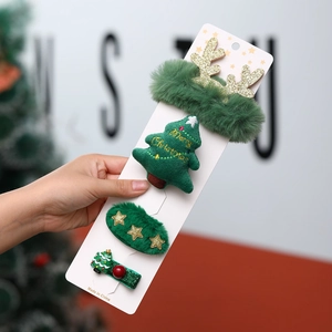 Detailed view of 4-piece green plush Christmas hair clip set with reindeer and tree motifs