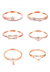 Detail view of various geometric rose gold bracelets with star, swan, and heart pendants