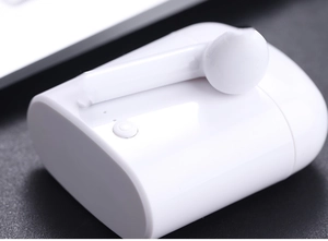 Primer plano de auricular inalámbrico blanco y estuche sobre fondo oscuro texturizado