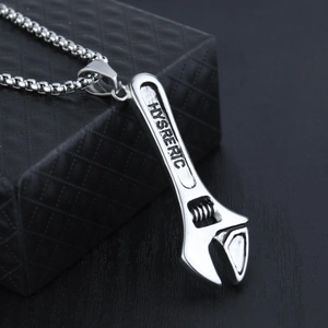 Macro shot of silver wrench pendant necklace with HYSRERIC engraving on black gift box