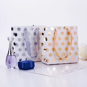Elegant polka dot paper gift bags with satin ribbons and gold foil detail for luxury packing