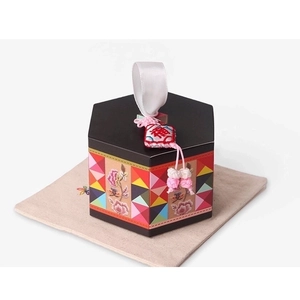 Detail view of a black hexagonal gift box with floral patterns and a Fu charm