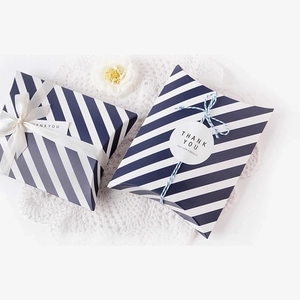 Striped pillow-shaped gift boxes with white ribbons and Thank You stickers on a lace mat