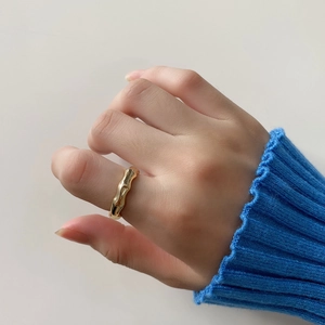 Close-up of gold organic bamboo texture ring on index finger with blue knit sleeve