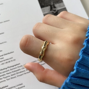 Close-up of golden bamboo-style sterling silver ring worn on a finger with a blue knit sleeve