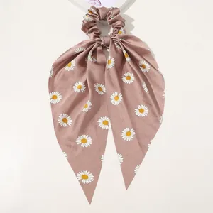 Detail of satin scrunchie with long ribbons and daisy print in dusty pink finish
