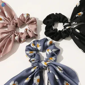 Detailed flat lay of daisy print satin scrunchies with long ribbons in pink, black and blue