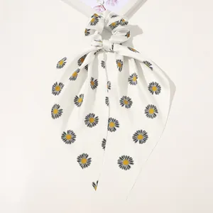 Detail showing smooth white satin hair scrunchie with yellow daisy print and long ribbons