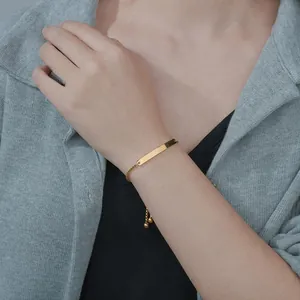 Close-up of a polished gold rectangular bar bracelet with adjustable pull-bead closure