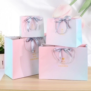 Pink gradient gift bags with silver ribbon handles and gold rich and colorful print